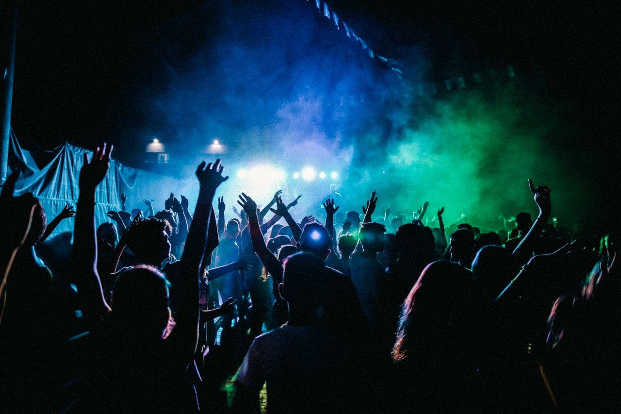Services Dynamic scene of a vibrant nightclub with a lively crowd enjoying live music and colorful lights.